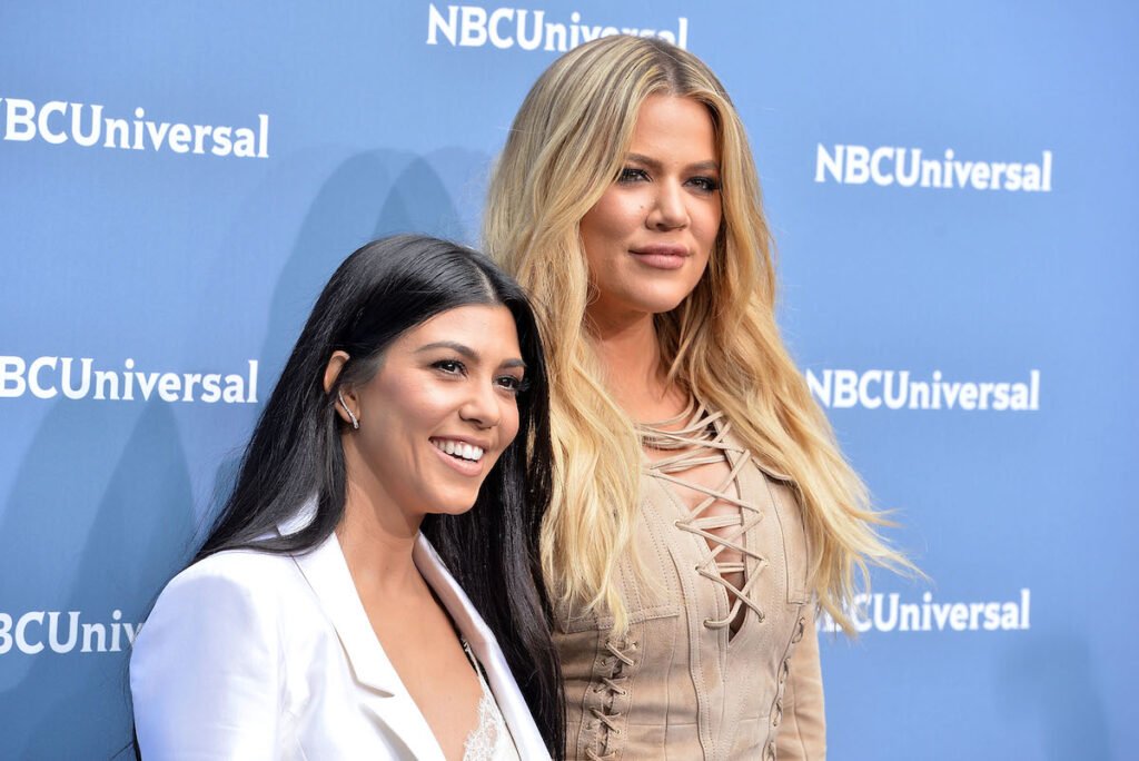 Kourtney Kardashian in a white jacket with Khloe Kardashian in a tan top