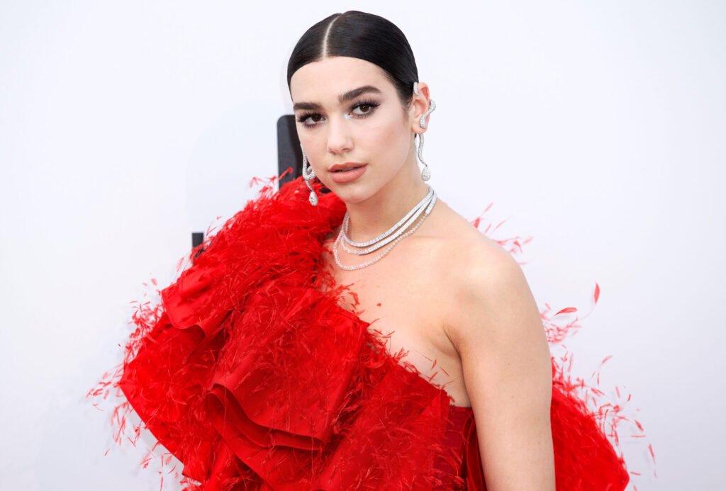 Dua Lipa in a ruffled red dress at a red carpet event.