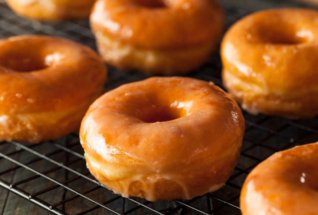 Round, glazed donuts on a wire cooling rack.