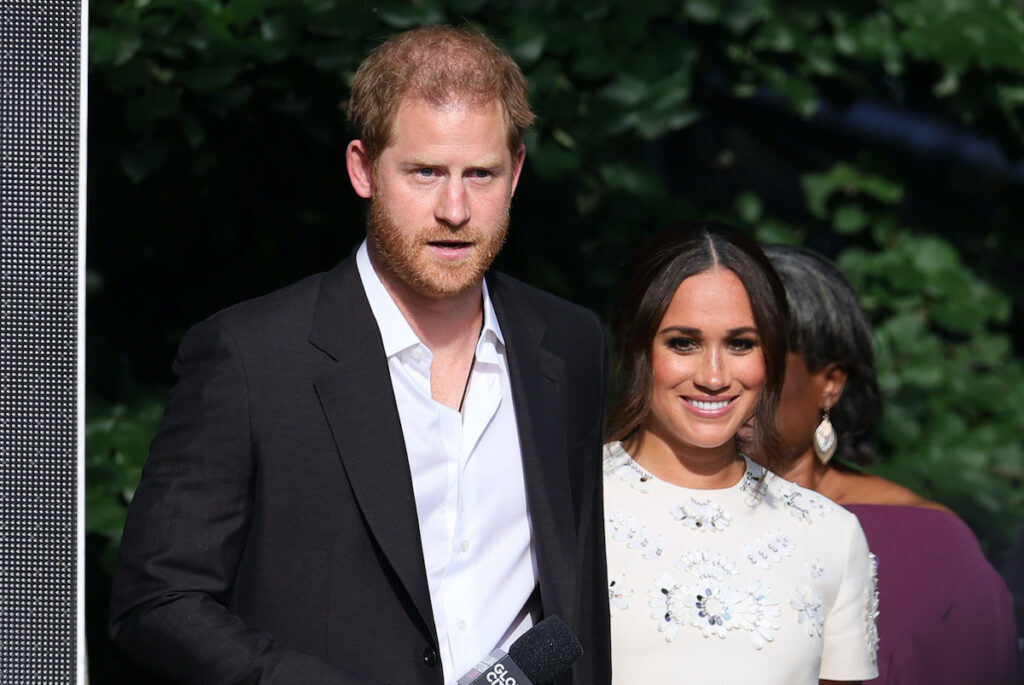 Prince Harry in a black suit with Meghan Markle in a white dress