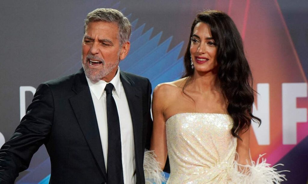 George Clooney in a black suit with Amal in a white dress