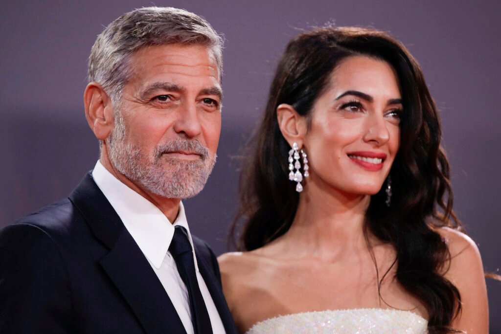 George Clooney in a black suit with Amal Clooney in a white dress