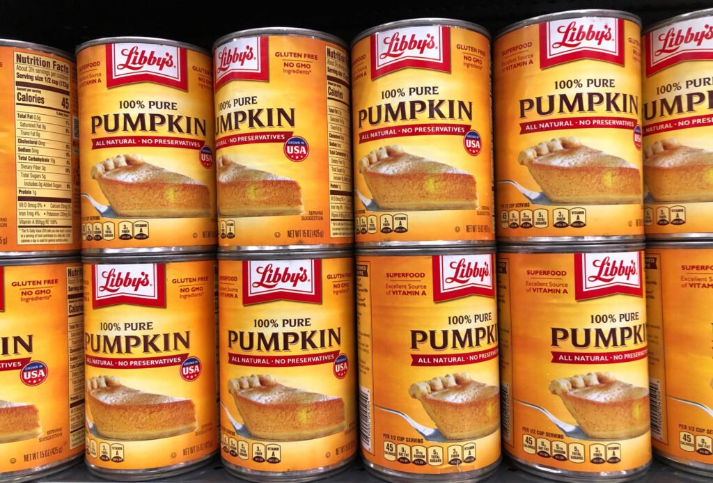 Canned pumpkin stacked on a store shelf.