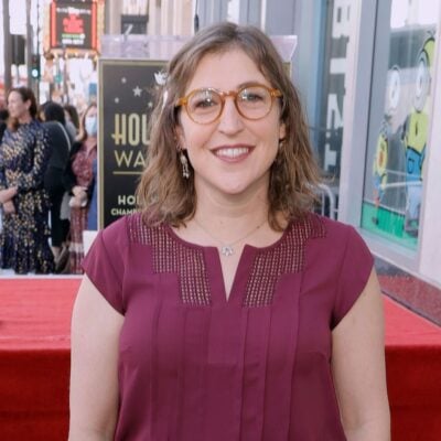 Mayim Bialik smiling in a red blouse