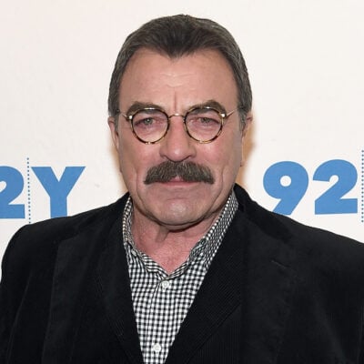 Tom Selleck in a black suit and plaid shirt