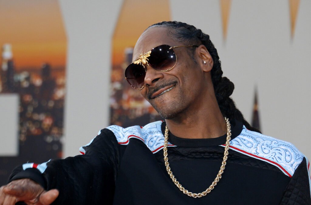 SnoopDogg in sunglasses smiling and pointing