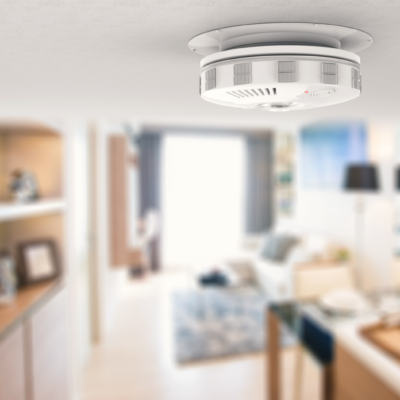 Carbon monoxide detector on ceiling with blurry living room background