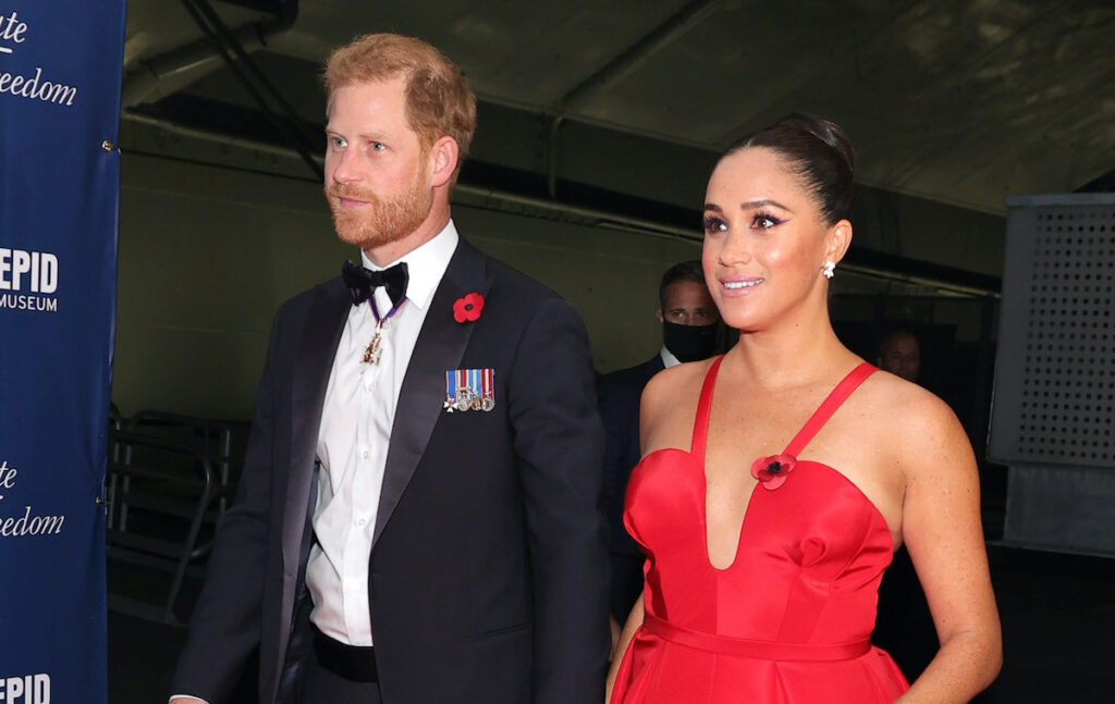 Prince Harry in a tuxedo with Meghan Markle in a red dress