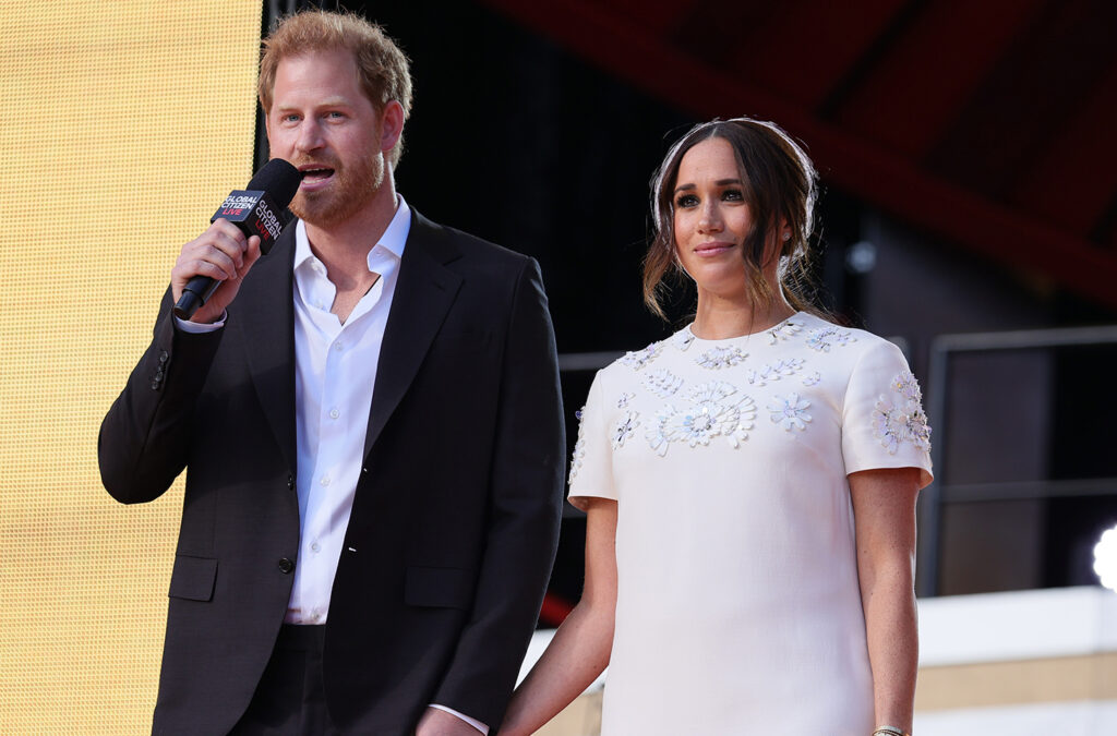 Prince Harry on the right with a microphone, Meghan Markle on the right, holding his hand.