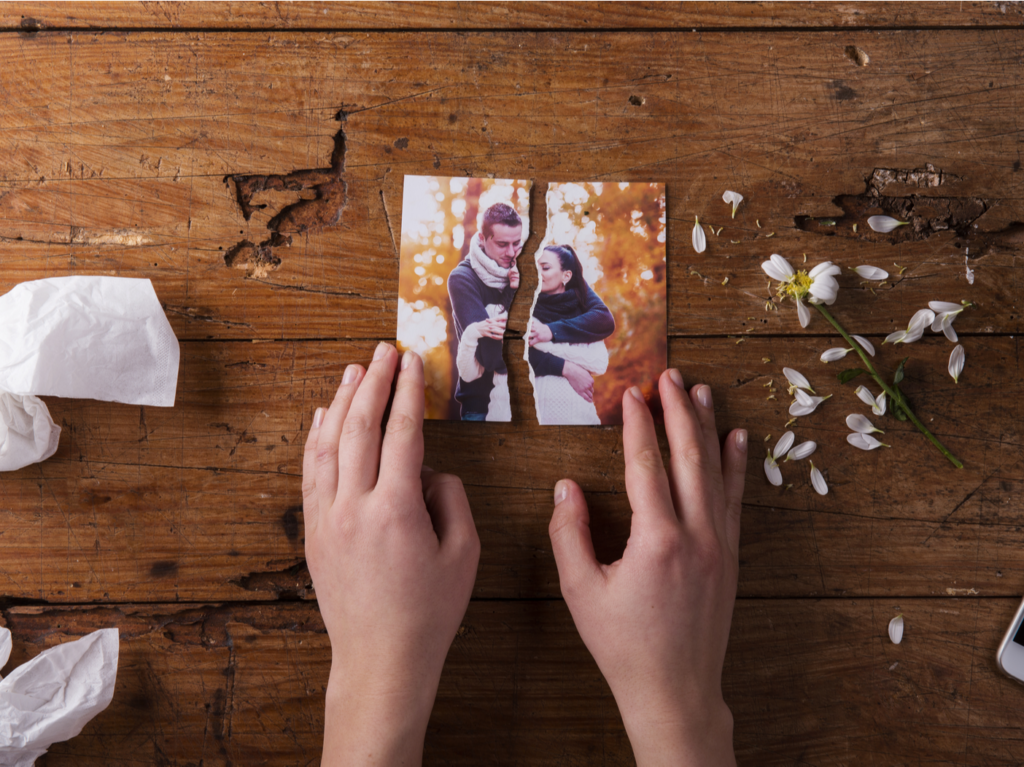 Unrecognizable sad woman holding torn picture of couple in love.