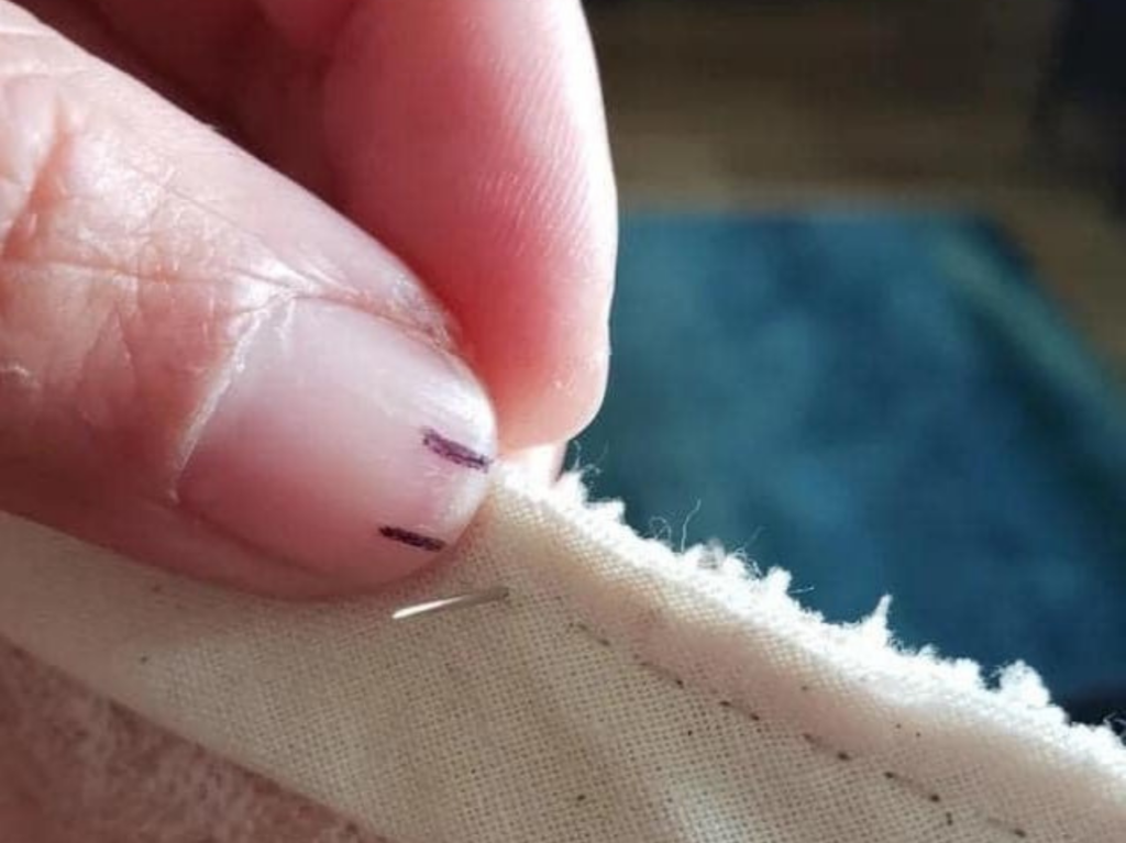 a hand sewing a straight line with hack