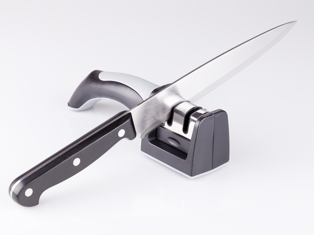 Knife and knife sharpener on a white surface. Kitchen tools isolated on white background.