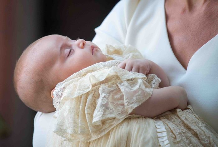 A small baby sleeps while wearing a christening gown