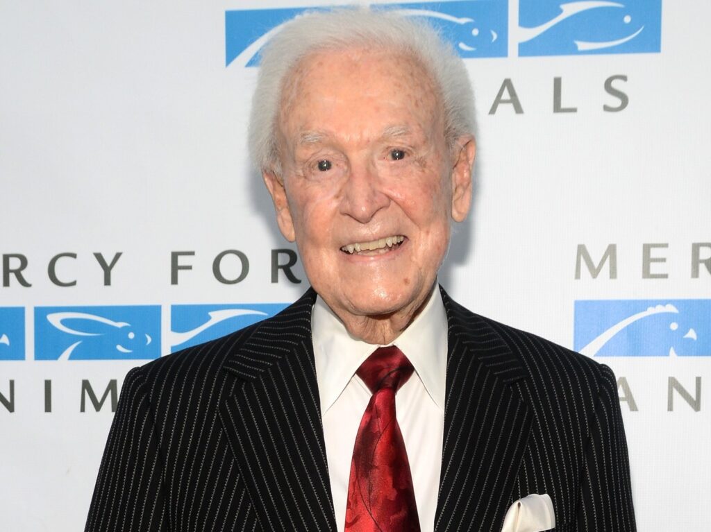 Bob Barker smiles wearing red tie with black blazer