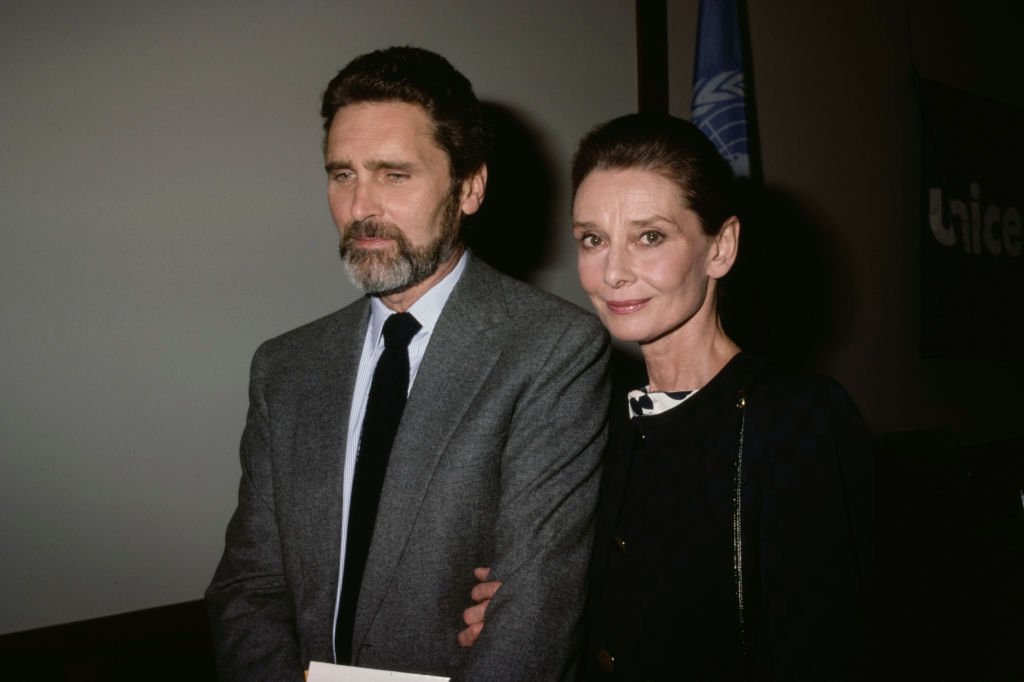 Robert Wolders and Audrey Hepburn walking arm in arm in 1988.