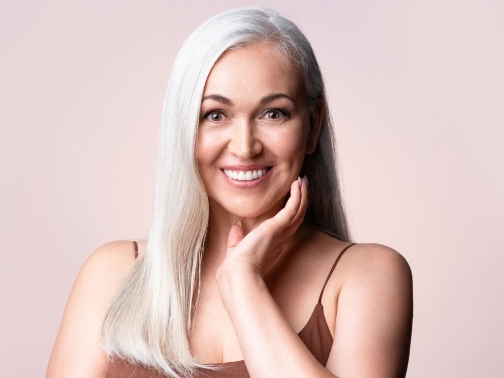 Gray-haired woman smiling, looking at camera.