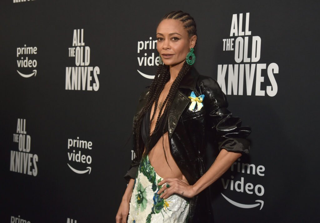 Thandiwe Newton posing in black jacket and green/white skirt against black background