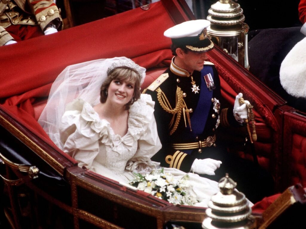 Princess Diana wears her iconic white wedding gown as she rides in a red-lined carriage with new husband Prince Charles