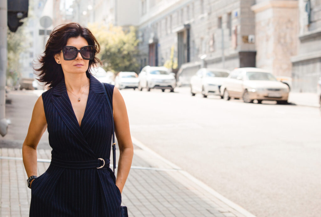 A woman walking down a city street in a navy jumpsuit.