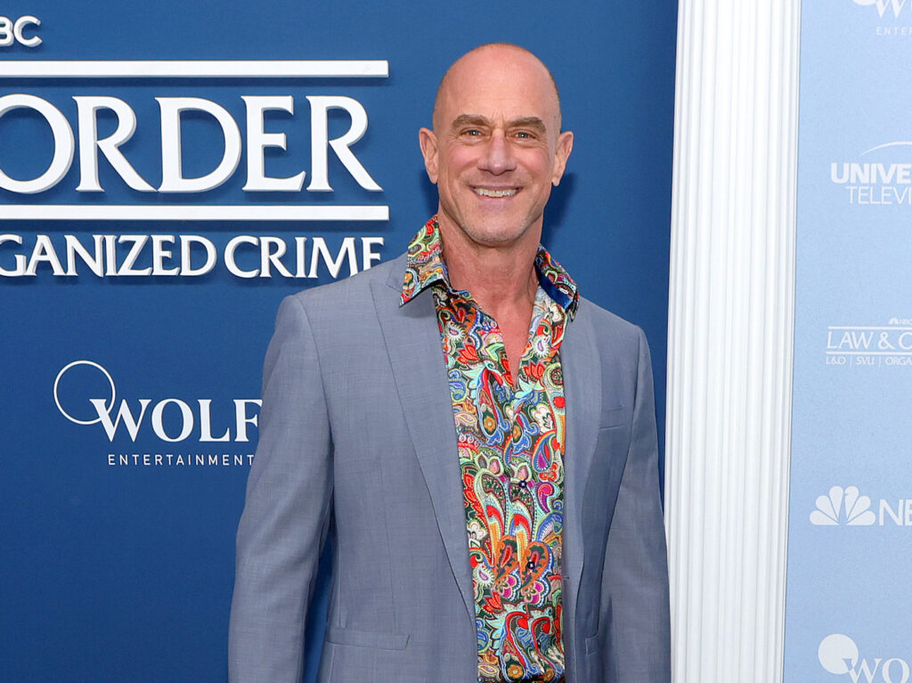 Christopher Meloni smiling in a grey jacket and colorful shirt