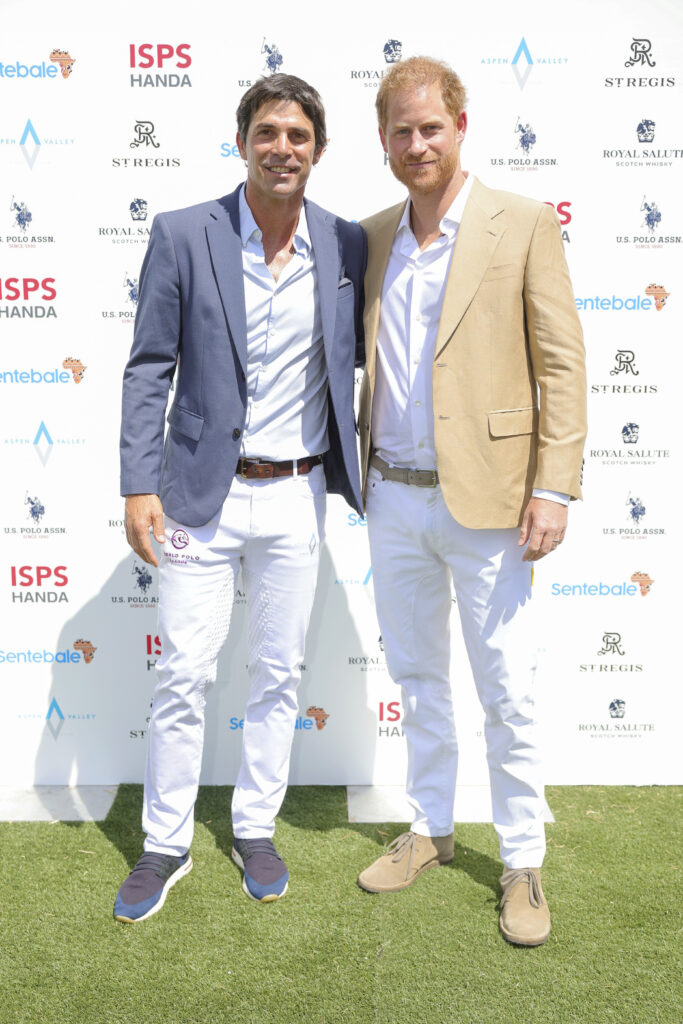 Prince Harry (R) in tan suit standing next to Nacho Figueras, who is wearing a gray suit