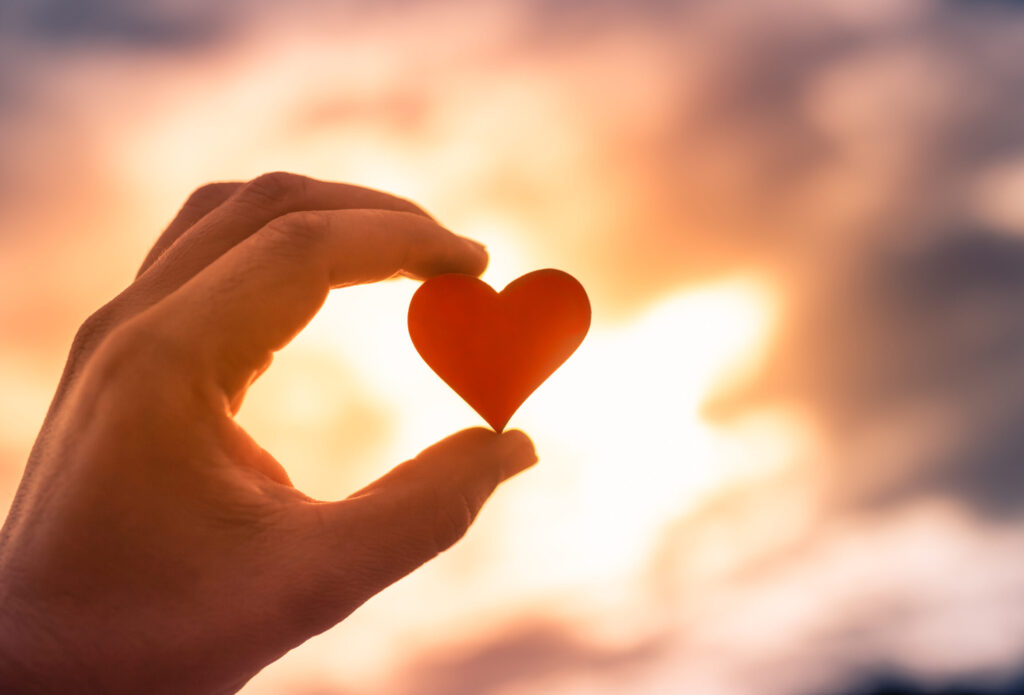 A hand holding a small paper heart