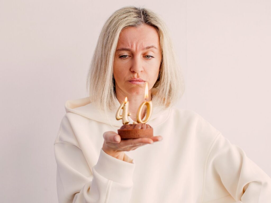 Woman unhappily looks at cupcake with "40" candles in it