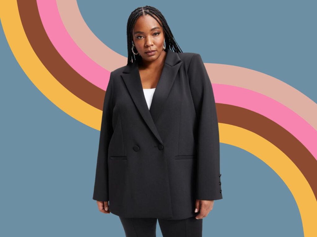 A Black woman with long braids wears a black suit