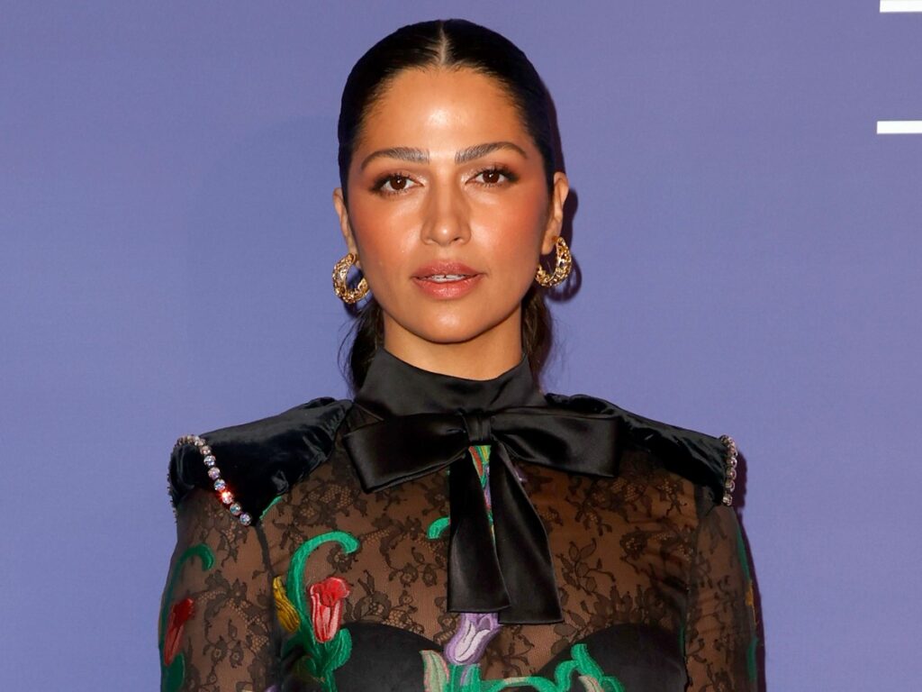 Camila Alves poses in black dress against purple backdrop