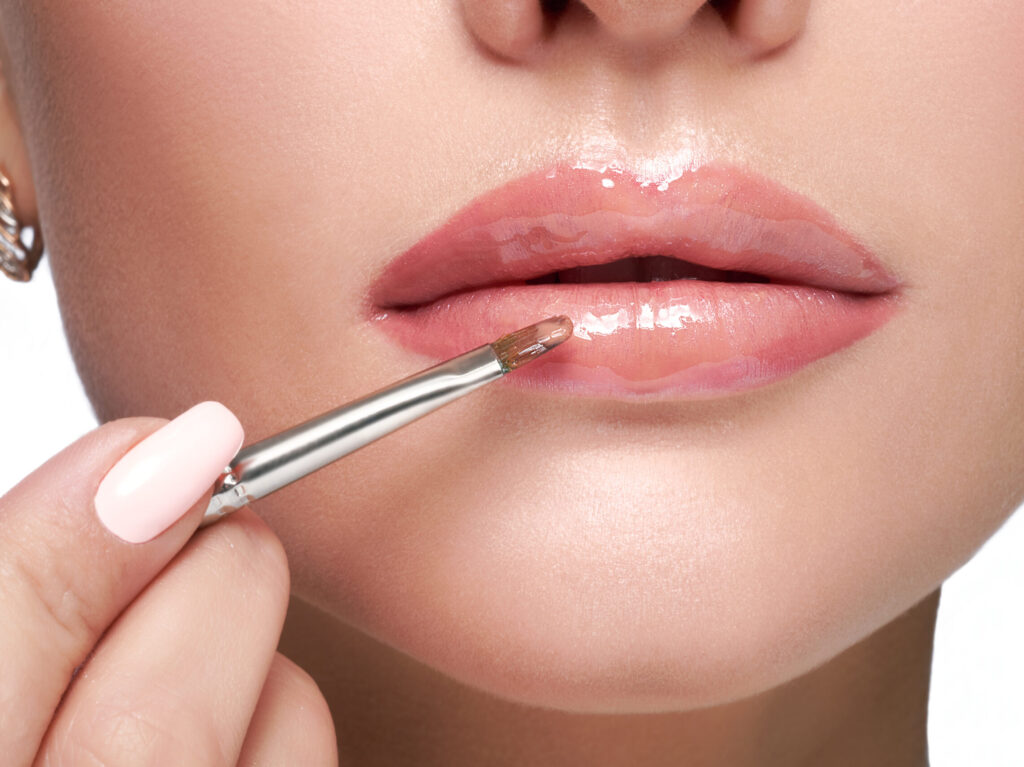 A woman applying a glossy lip product