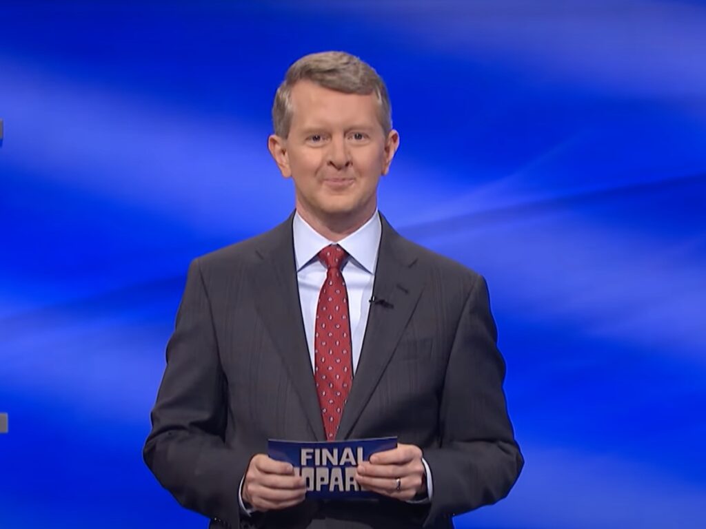 screenshot of Ken Jennings hosting Jeopardy! in a gray suit