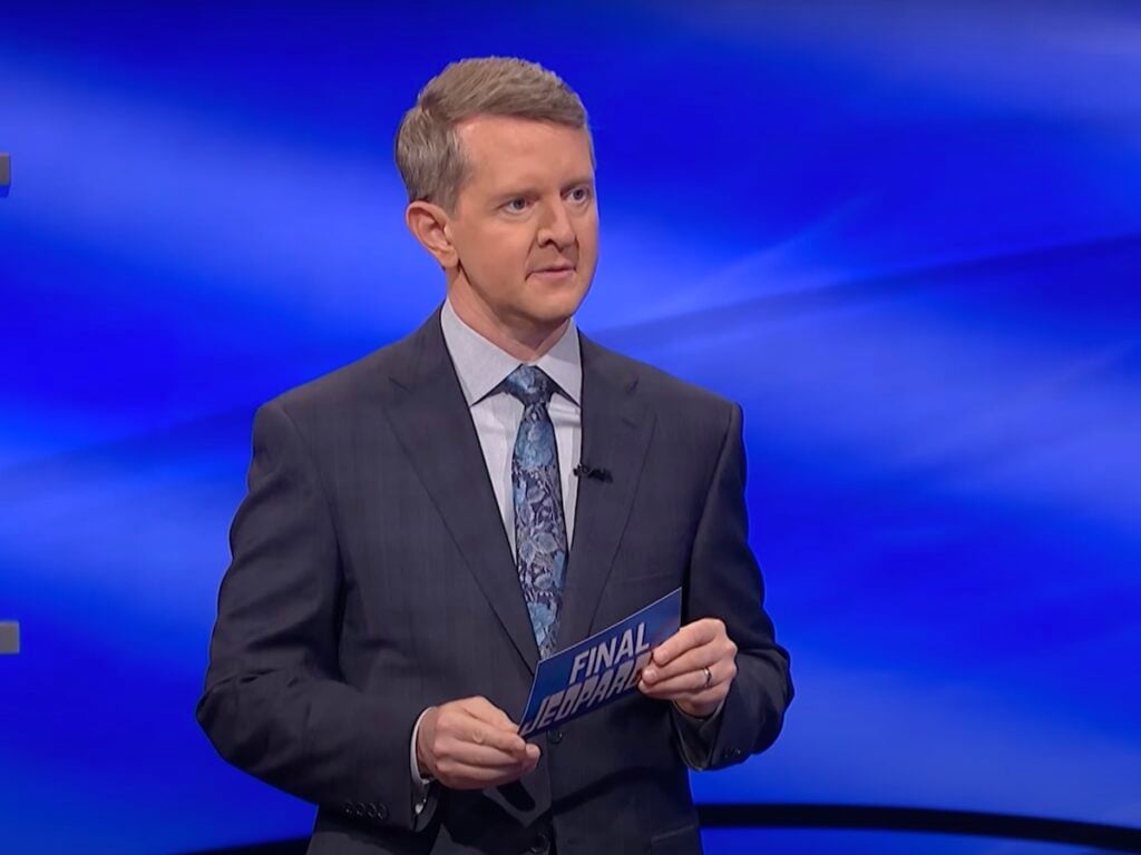 screenshot of Ken Jennings hosting Jeopardy! in a gray suit