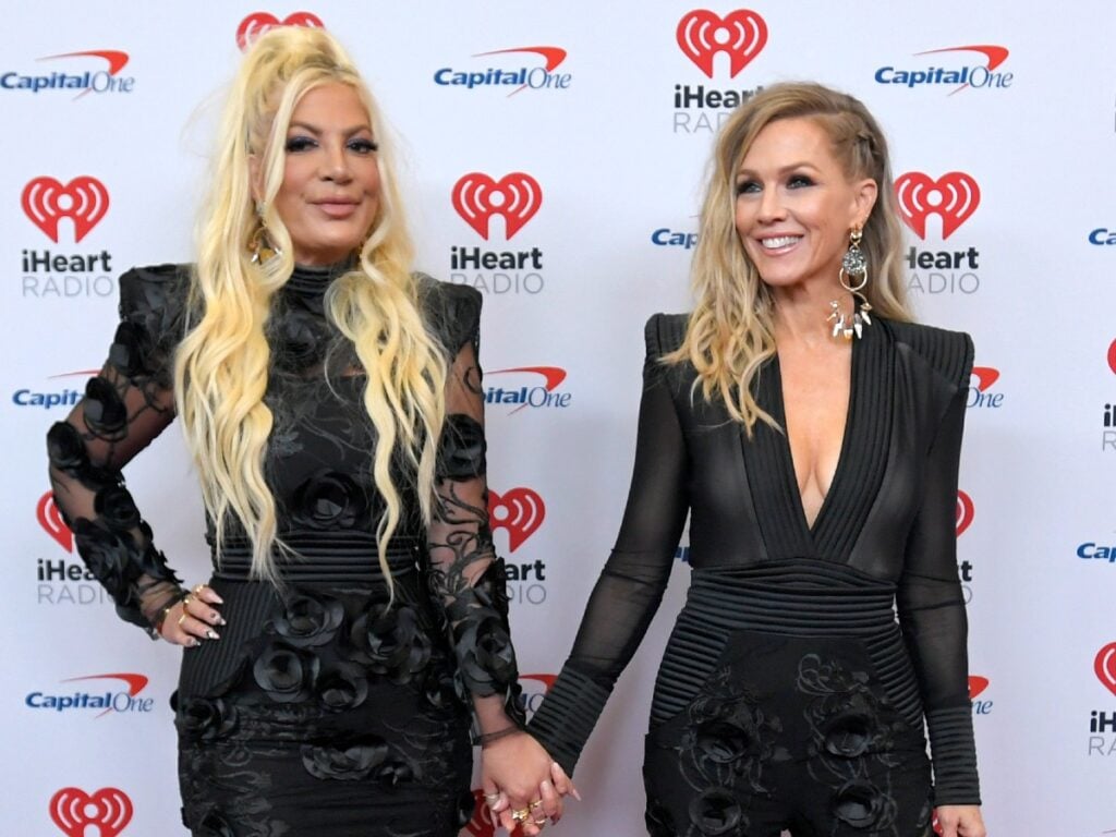 Tori Spelling (L) and Jennie Garth posing against white backdrop