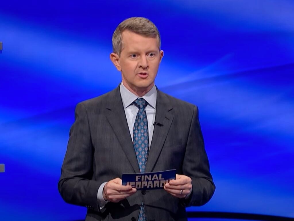 screenshot of Ken Jennings hosting Jeopardy! in a gray suit