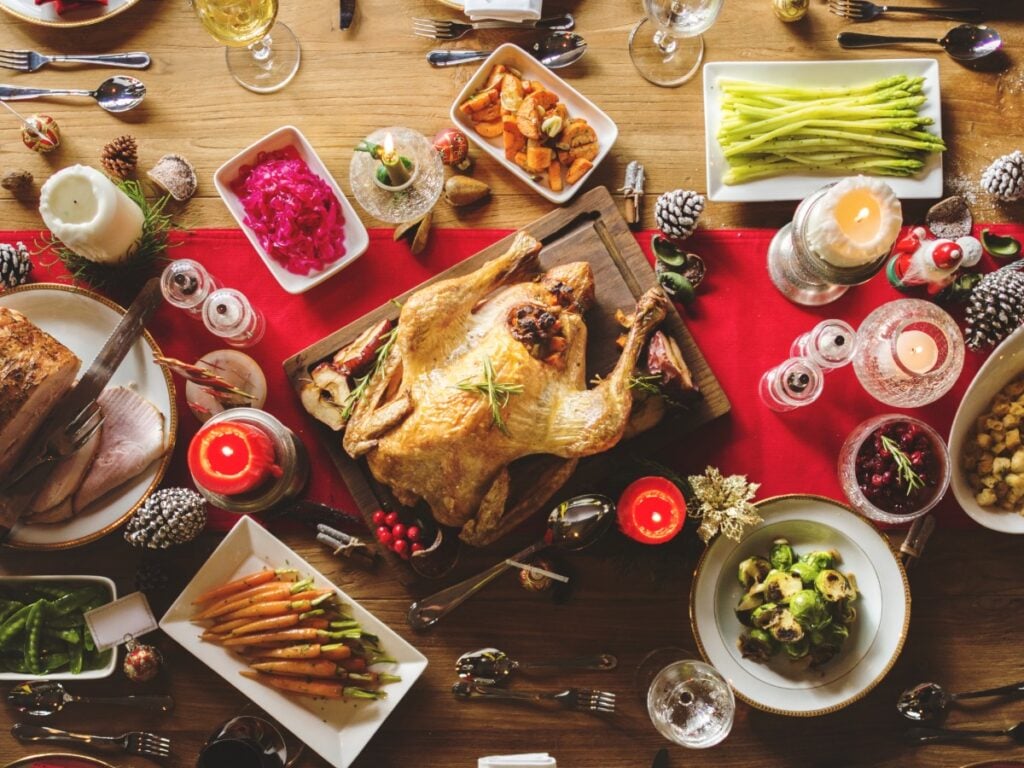 Overhead view of a Christmas dinner table set with a turkey and various sides